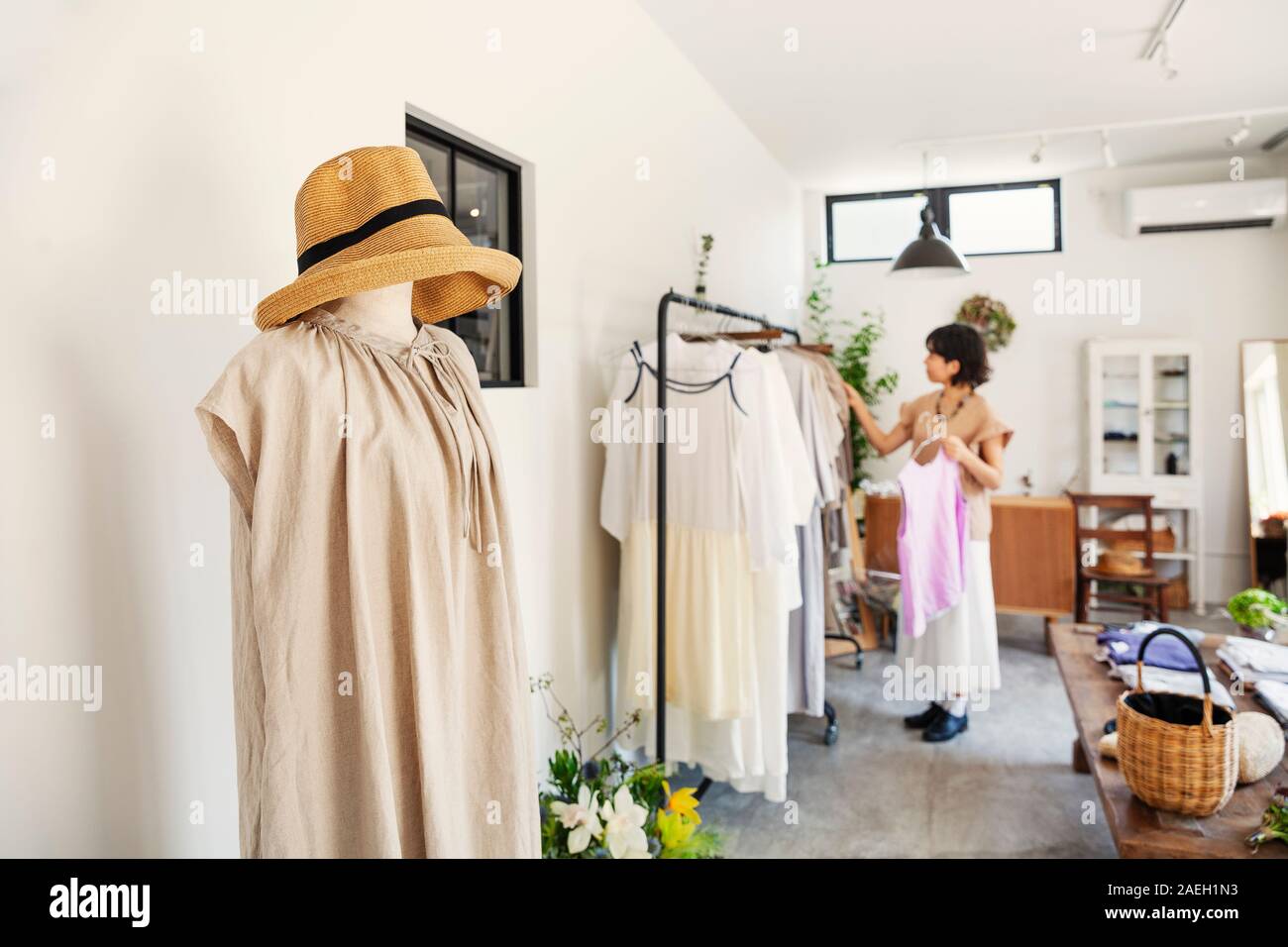 Japanische Frau, die in einer Boutique, an Kleidung auf einer Schiene. Stockfoto