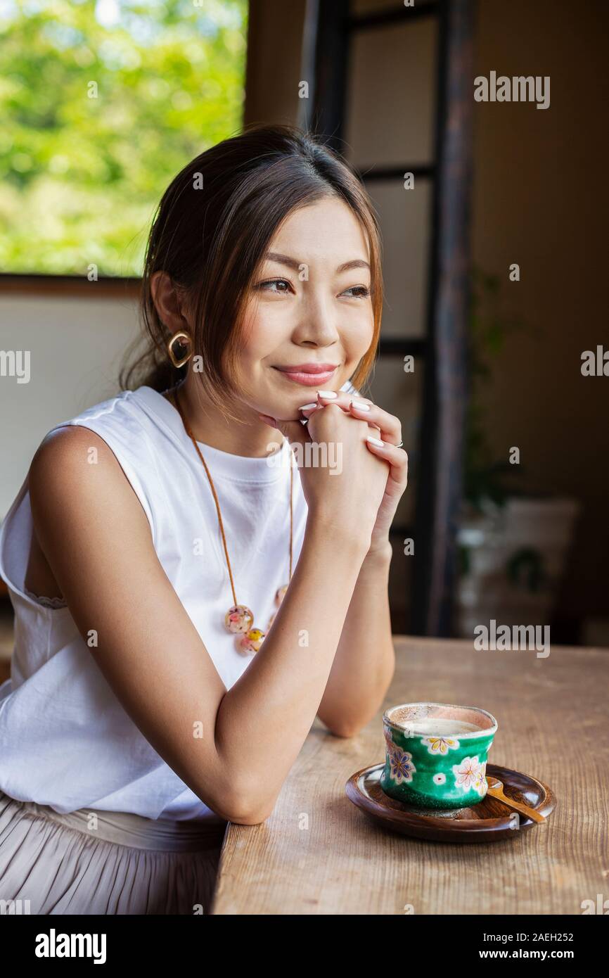 Lächelnd japanischen Frau am Tisch sitzend in ein japanisches Restaurant. Stockfoto
