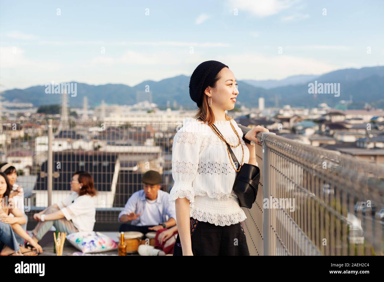 Lächelnde junge japanische Frau, die auf einem Dach in der Stadt. Stockfoto