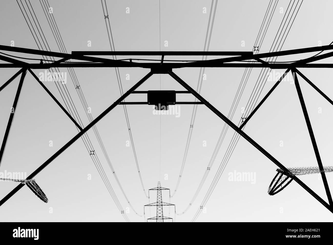 Schwarz-weiß Foto von Strommasten und Stromkabel Silhouette gegen den wolkenlosen Himmel mit führenden Leitungen Stockfoto