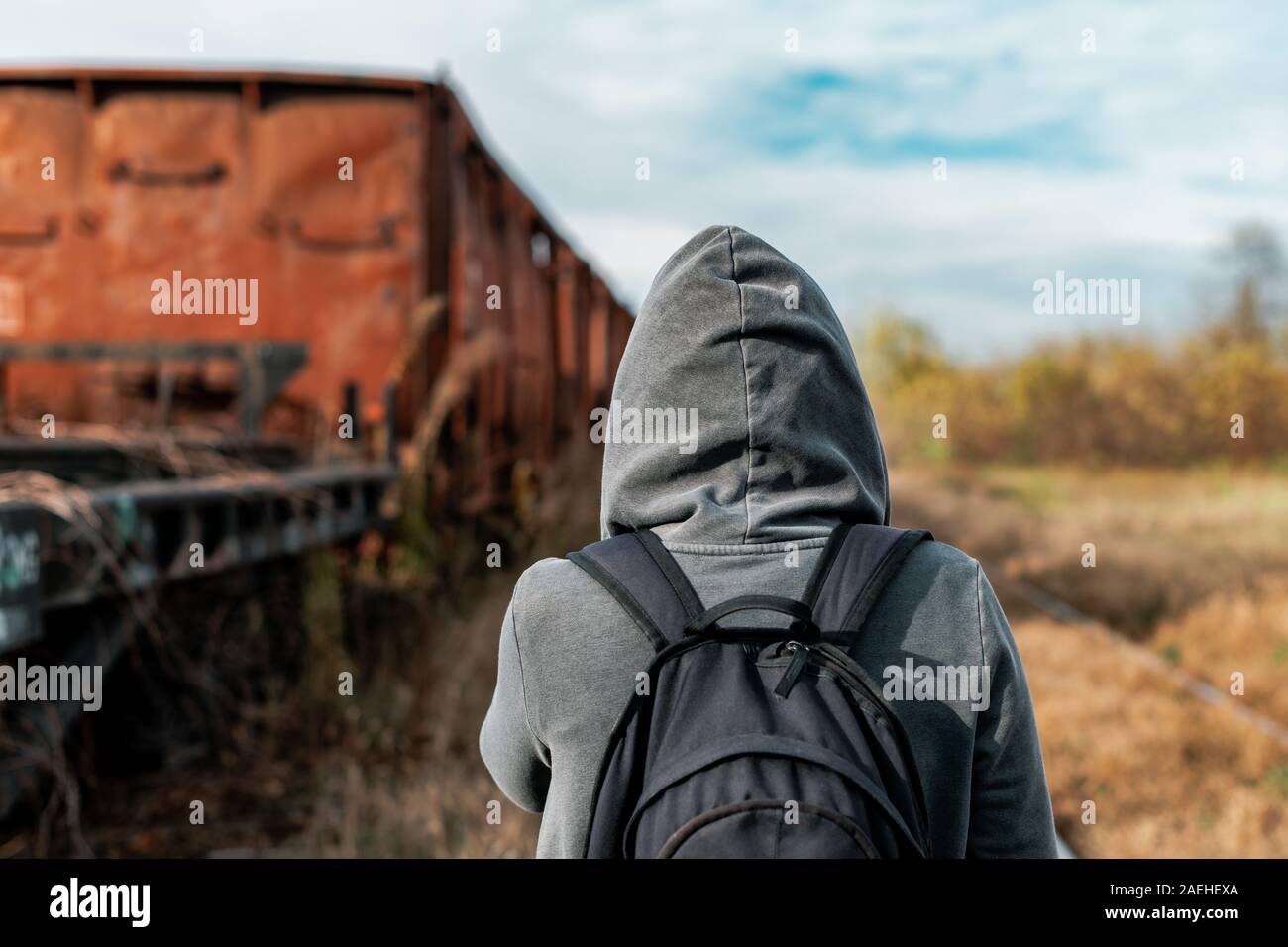 Obdachlose Frau mit Rucksack Entfliehen, Rückansicht der weiblichen Fuß unter verlassenen Waggons und veraltete Eisenbahn Stockfoto