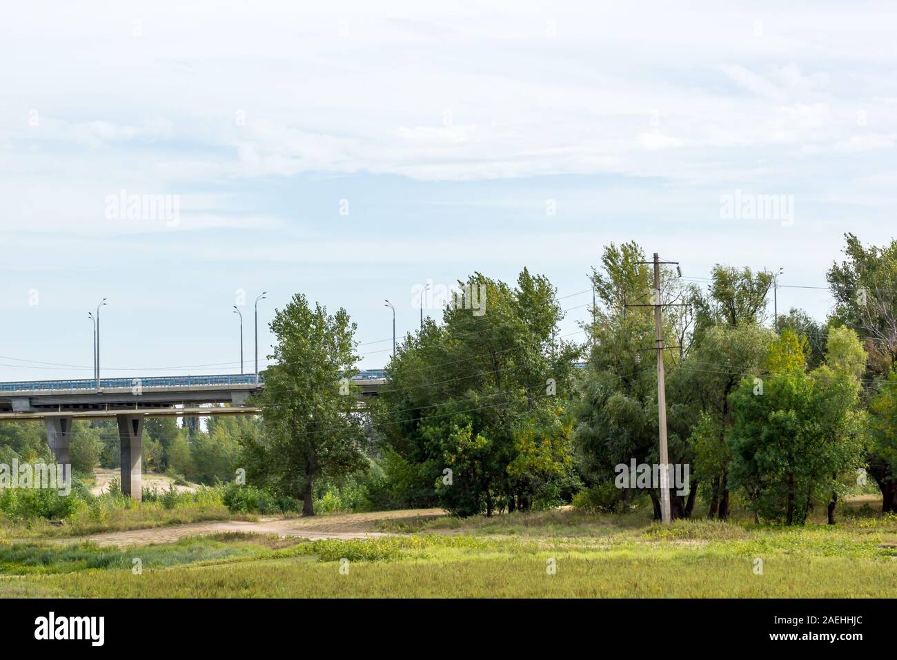 Straße Brücke, die durch ein Feld mit Bäumen und Sträuchern. Panorama. Stockfoto