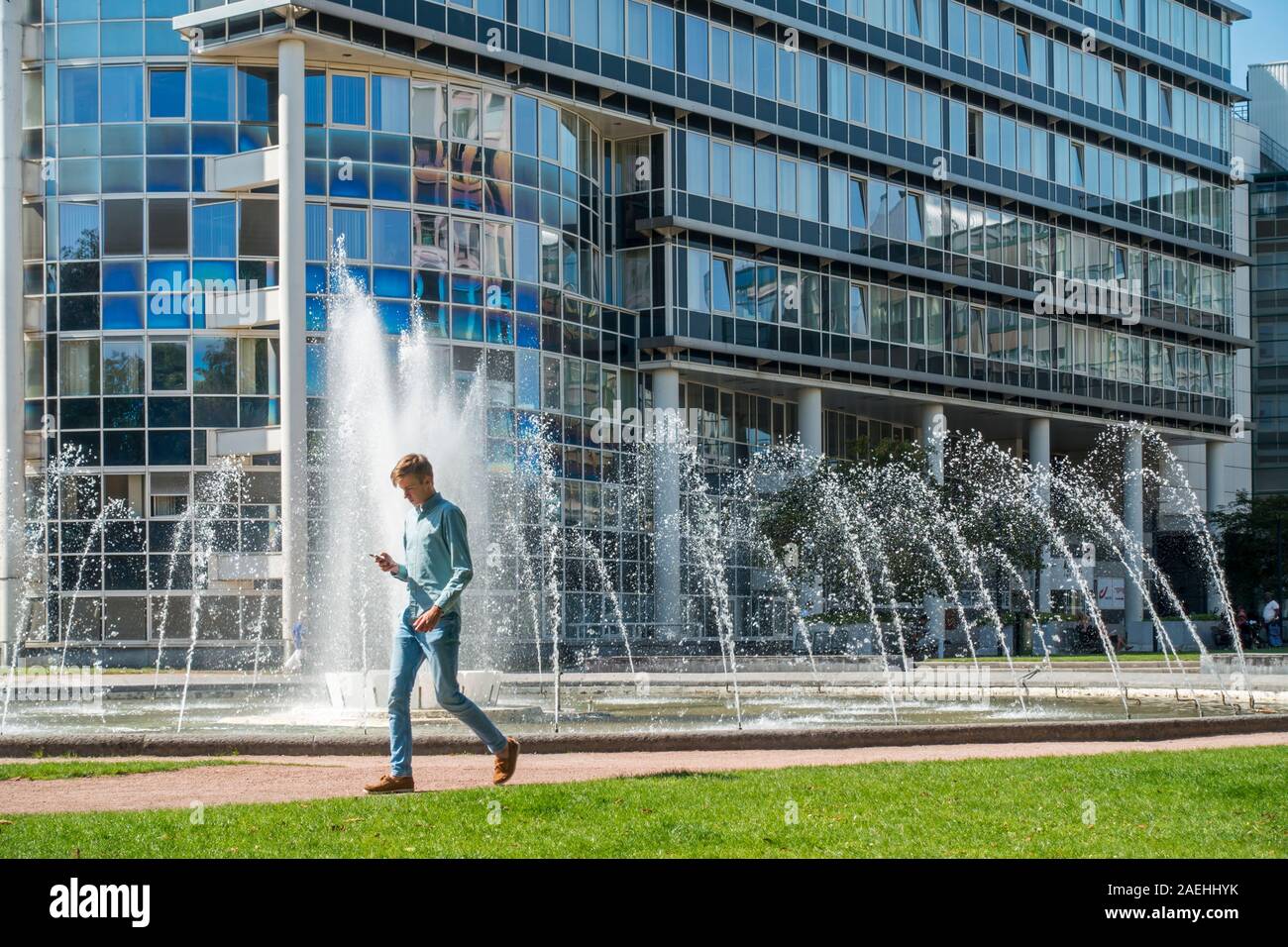 Man Walking beim Lesen Smartphone vor Brunnen in der König Albert Park, City Park im Süden Bezirk an, Gent, Ostflandern, Belgien Stockfoto