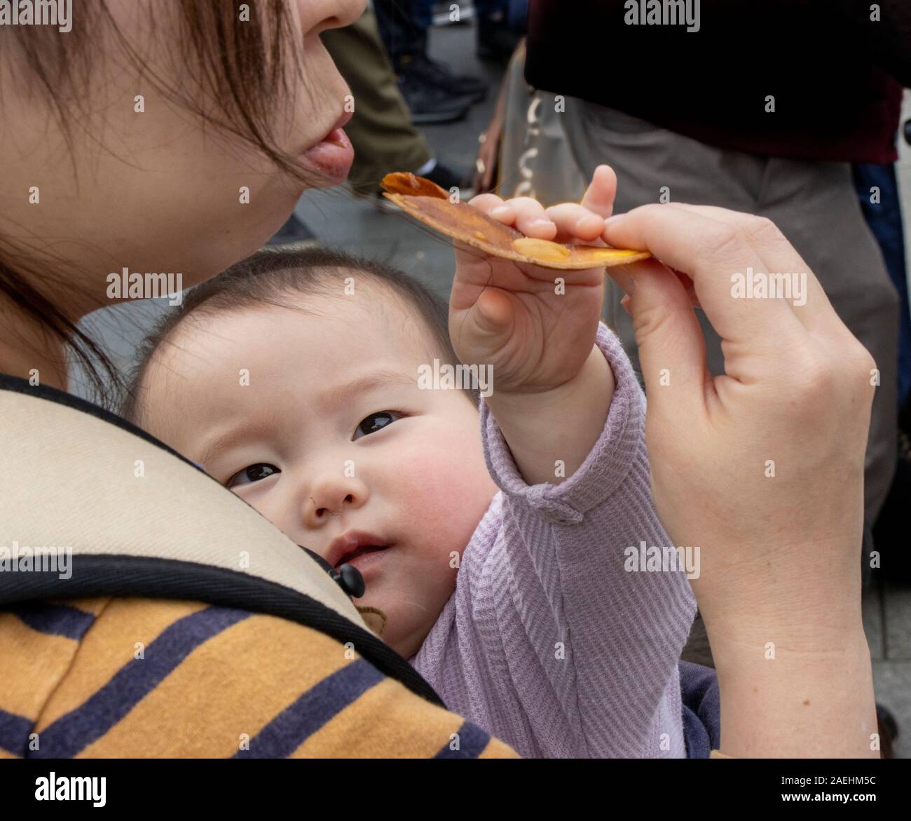 Baby erreichen für Lebensmittel, die Mutter ist Essen, Tokio, Japan Stockfoto