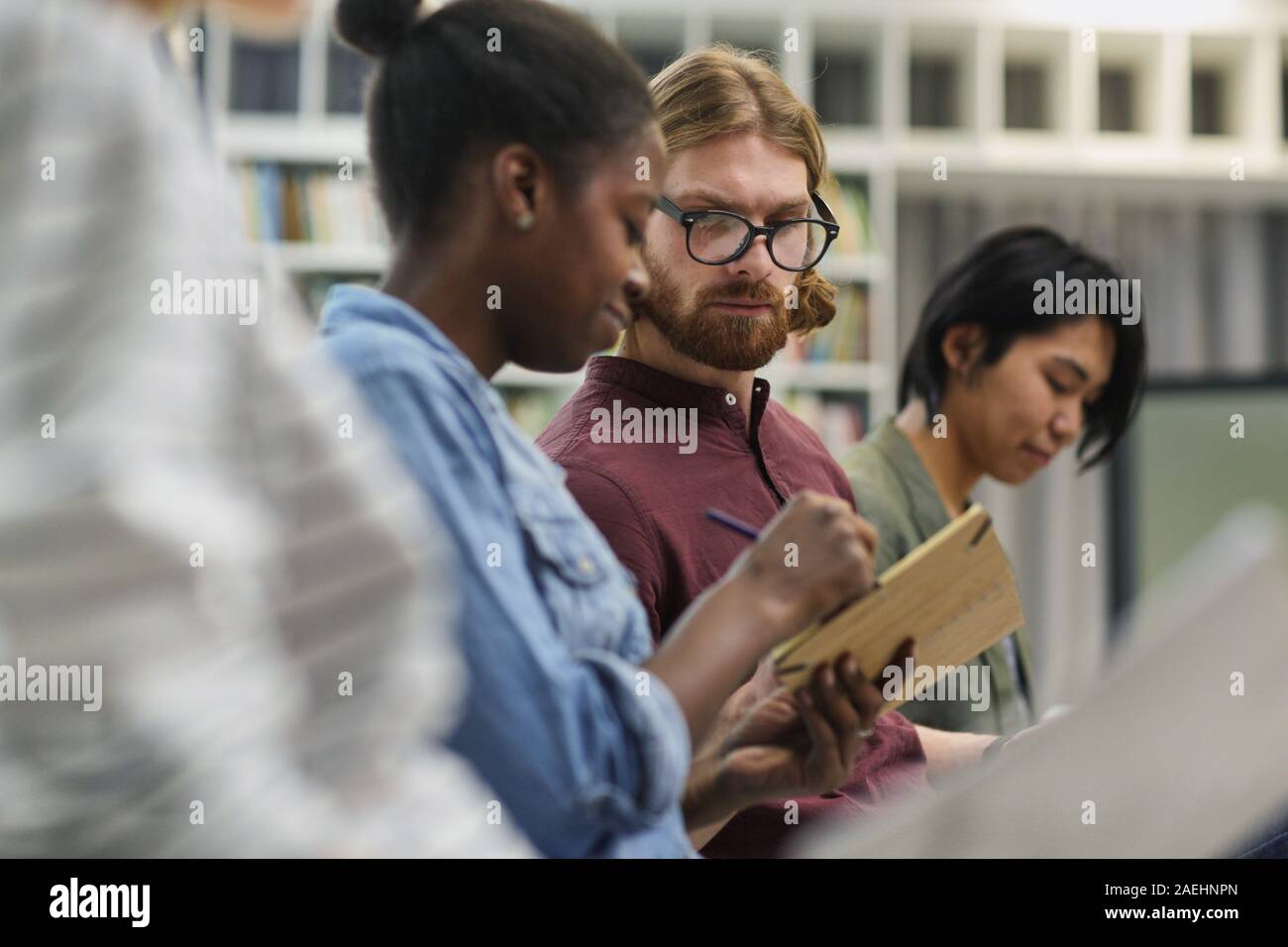 Junger Mann in Brillen Beratung mit seinem Kollegen und sie zeigten ihm ihre Schriften an Vortrag Stockfoto
