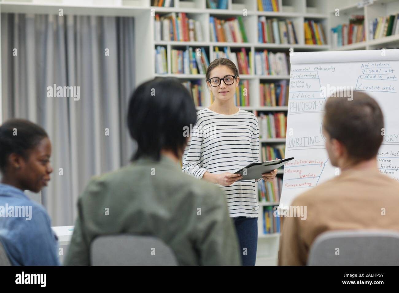 Junge Frau in Brillen stehen in der Nähe der Tafel und die Vorlage ihres Berichts über Geschäftsleute, während einer Präsentation Stockfoto