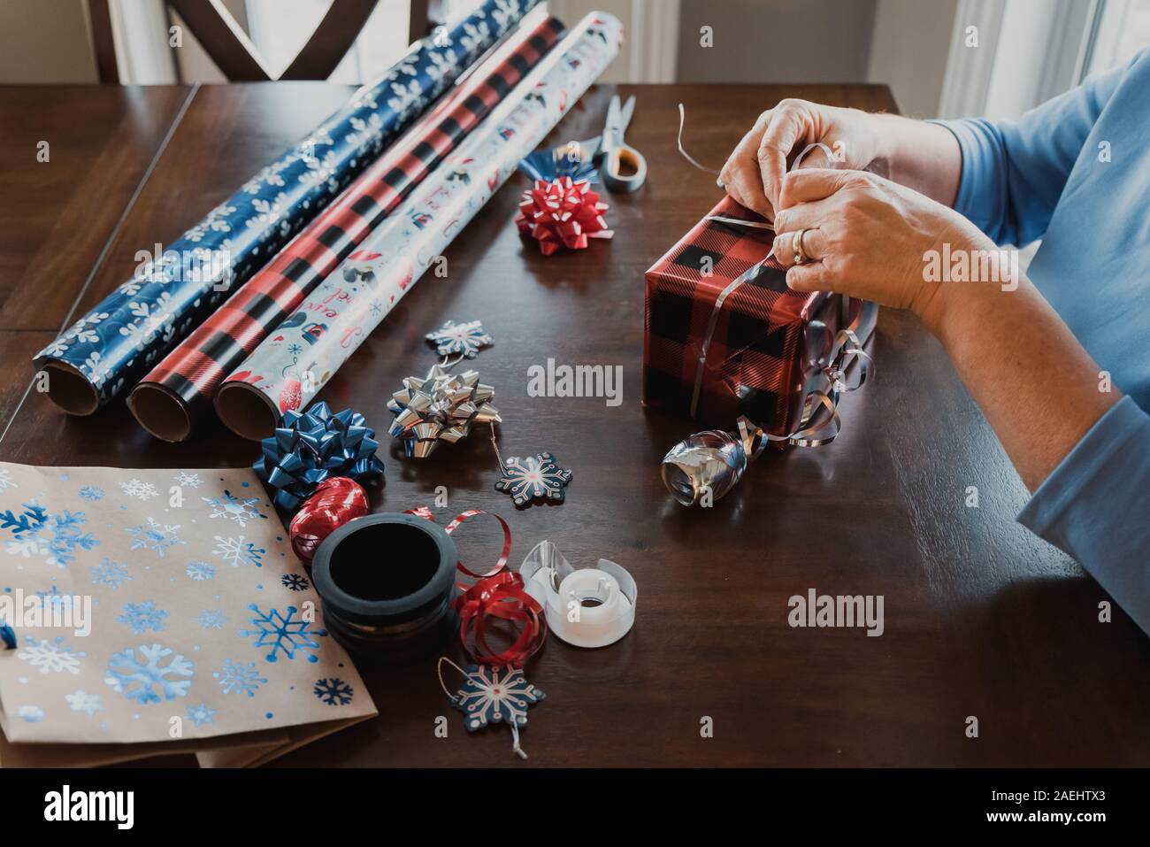 Hände wickeln mit Geschenkverpackung liefert auf Tisch. Stockfoto