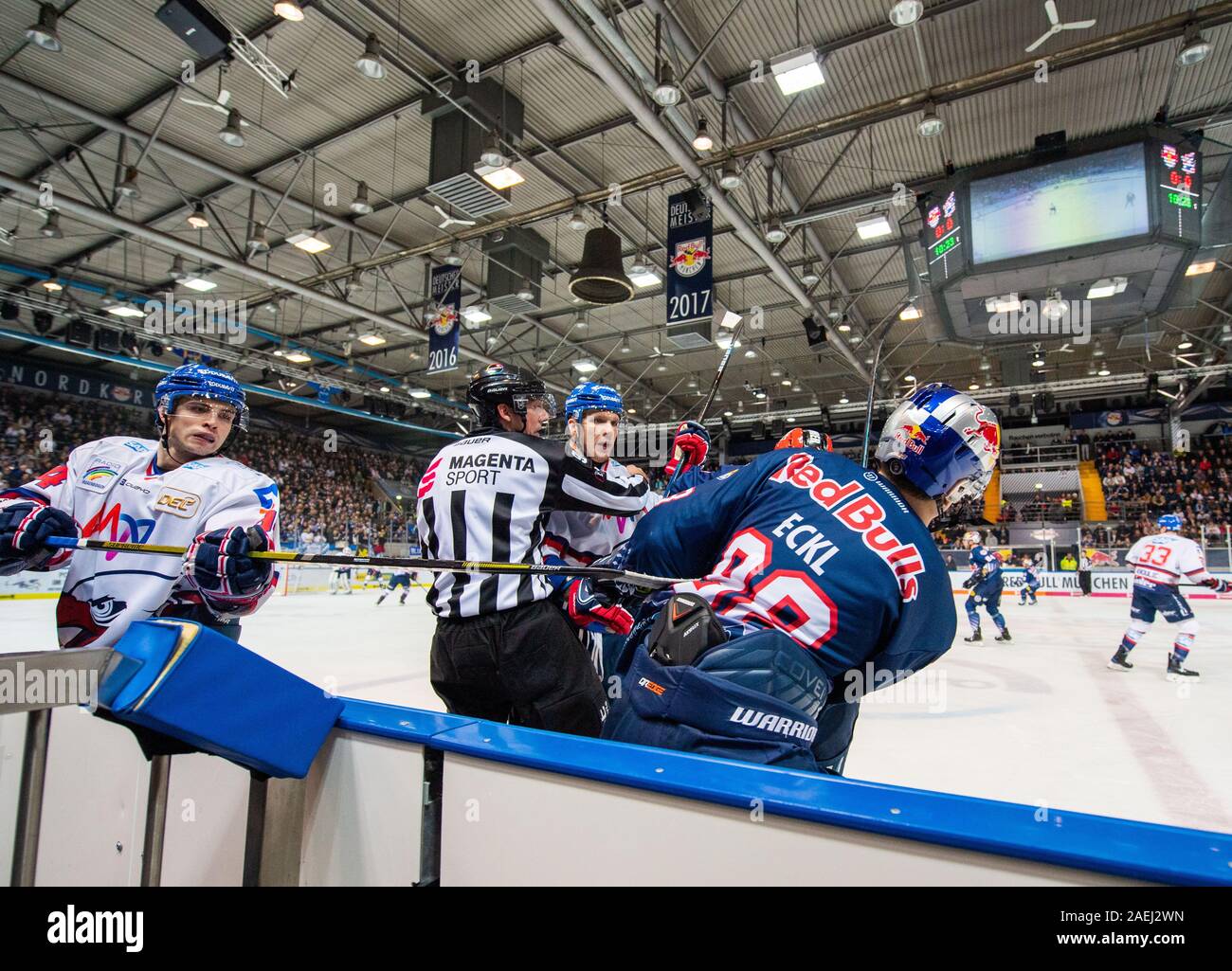 München, Deutschland. 08 Dez, 2019. Eishockey: DEL, EHC Red Bull München - Adler Mannheim, Hauptrunde, 25. Spieltag in der olympischen Eisstadion München. David Wolf von Adler Mannheim (m) wird von Bastian Eckl von Red Bull München gehalten von einem Schiedsrichter nach einer Karosserie prüfen. Credit: Lino Mirgeler/dpa/Alamy leben Nachrichten Stockfoto