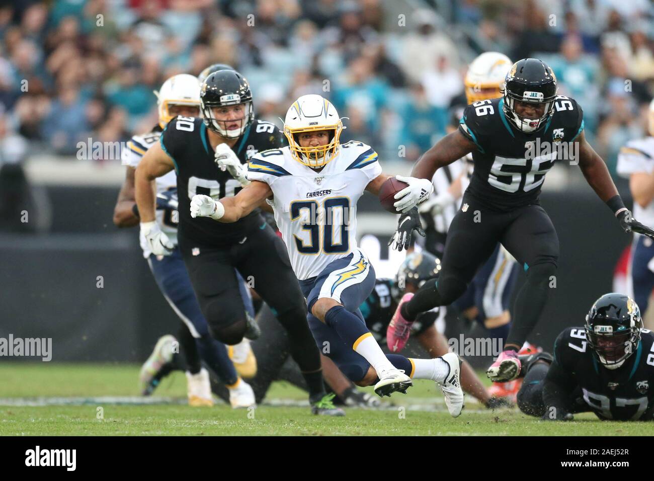 Sonntag, 8. Dezember 2019; Jacksonville, FL, USA; Los Angeles Ladegeräte zurück Austin Ekeler (30) läuft mit dem Ball, während durch Jacksonville Jaguars defensiver Taven Bryan (90) und linebacker Quincy Williams (56) Während ein NFL Spiel bei tiaa Bank Bereich verfolgt. Die Ladegeräte schlagen die Jaguare 45-10. (Kim Hukari/Image des Sports) Foto per Kreditkarte: Newscom/Alamy leben Nachrichten Stockfoto
