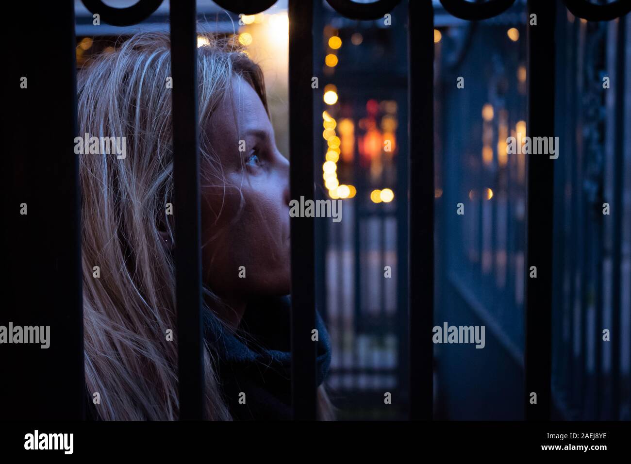 Nachdenkliche Frau hinter einem Zaun Stockfoto