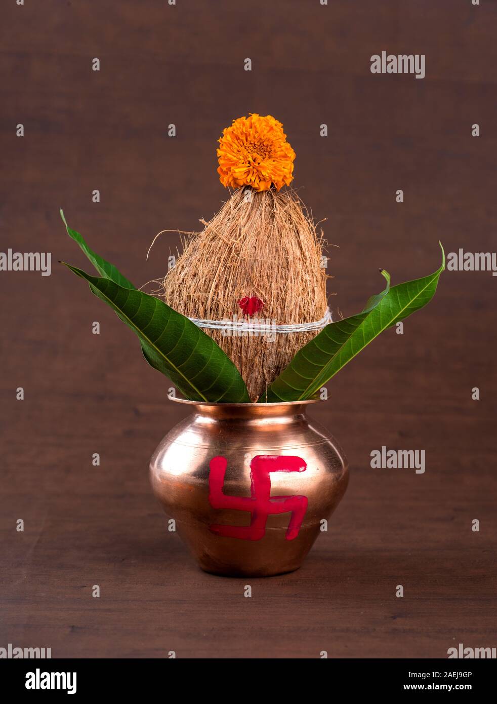 Kupfer kalash mit Kokos und Mango leaf mit Blumendekor auf einer hölzernen Hintergrund. Wesentlichen in der hinduistischen Puja. Stockfoto