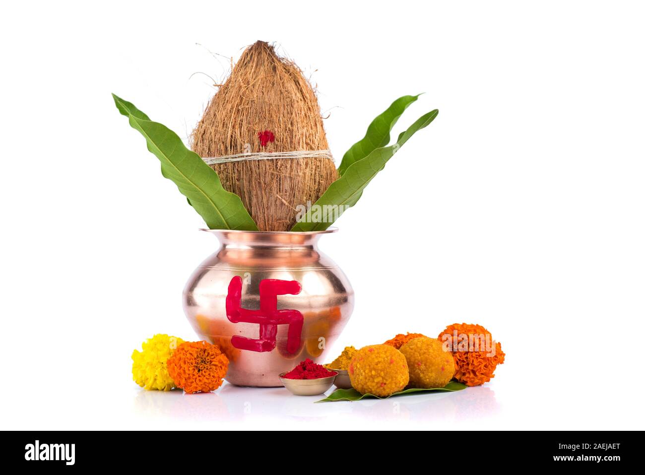 Kupfer Kalash mit Kokos, mango Leaf, Haldi, Kumkum und Süßigkeiten mit Ringelblume Blumendekoration auf einem weißen Hintergrund. Wesentlich in der hinduistischen Puja. Stockfoto