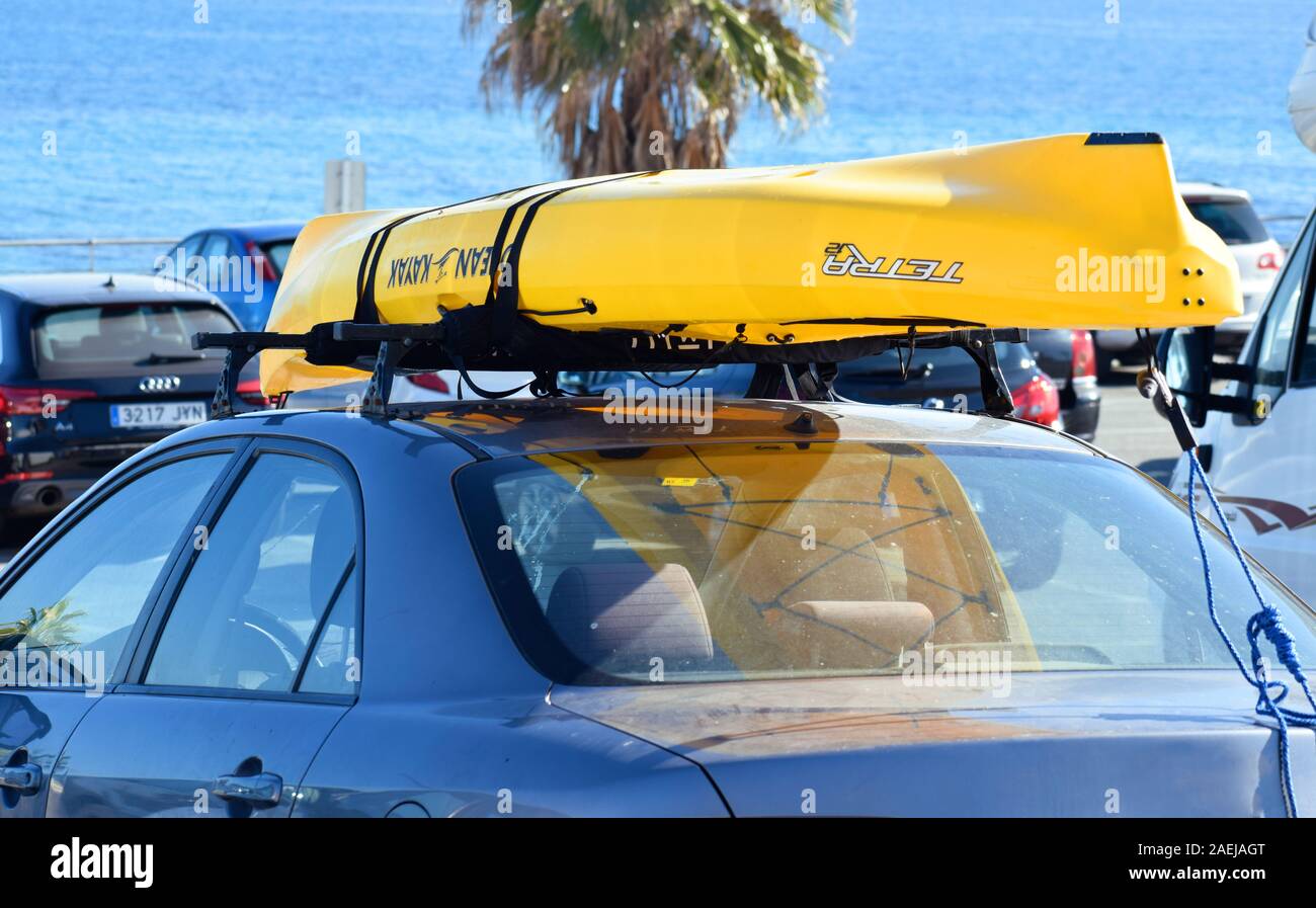 Murcia, Spanien, 20. August 2019: Gelb mit dem Kajak auf dem Dachgepäckträger gegen Palmen gebunden, und die Marine in Barcelona, Spanien. Stockfoto