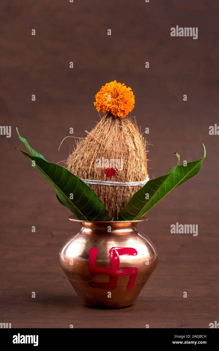 Kupfer kalash mit Kokos und Mango leaf mit Blumendekor auf einer hölzernen Hintergrund. Wesentlichen in der hinduistischen Puja. Stockfoto