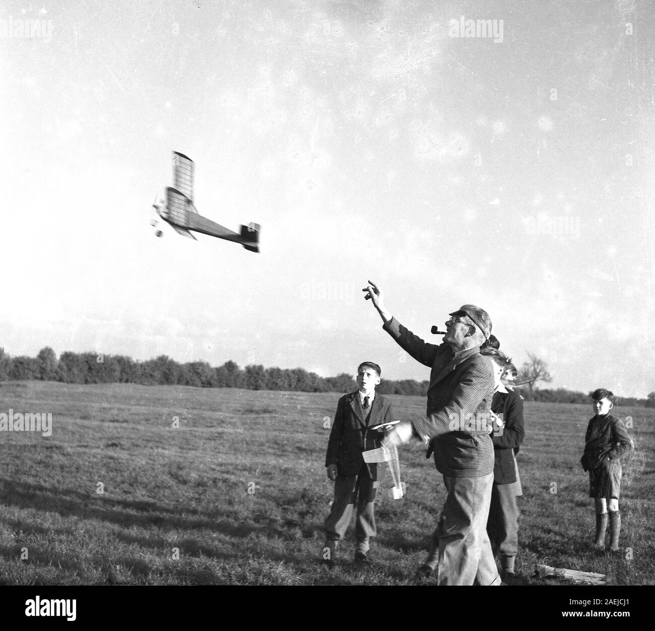1950, historische, draussen auf einer Wiese, einige Jungen auf der Suche nach einem Erwachsenen Enthusiast ein flugmodell Flugzeug in die Luft, England, Großbritannien startet. Stockfoto