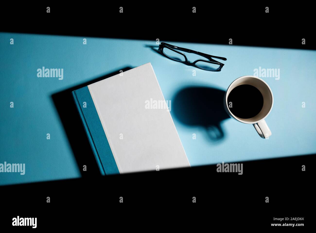 Ein Schimmer von Licht auf das weiße Buch und auf der Tasse Kaffee Stockfoto