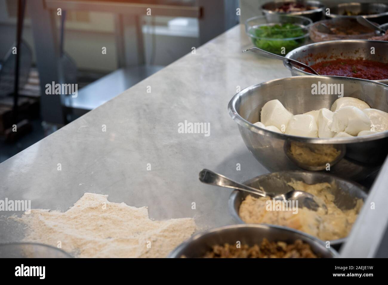 Pizza Chef (PIZZAIOLO) Marmor. Mozzarella, Tomaten und andere Zutaten in den Vordergrund Stockfoto