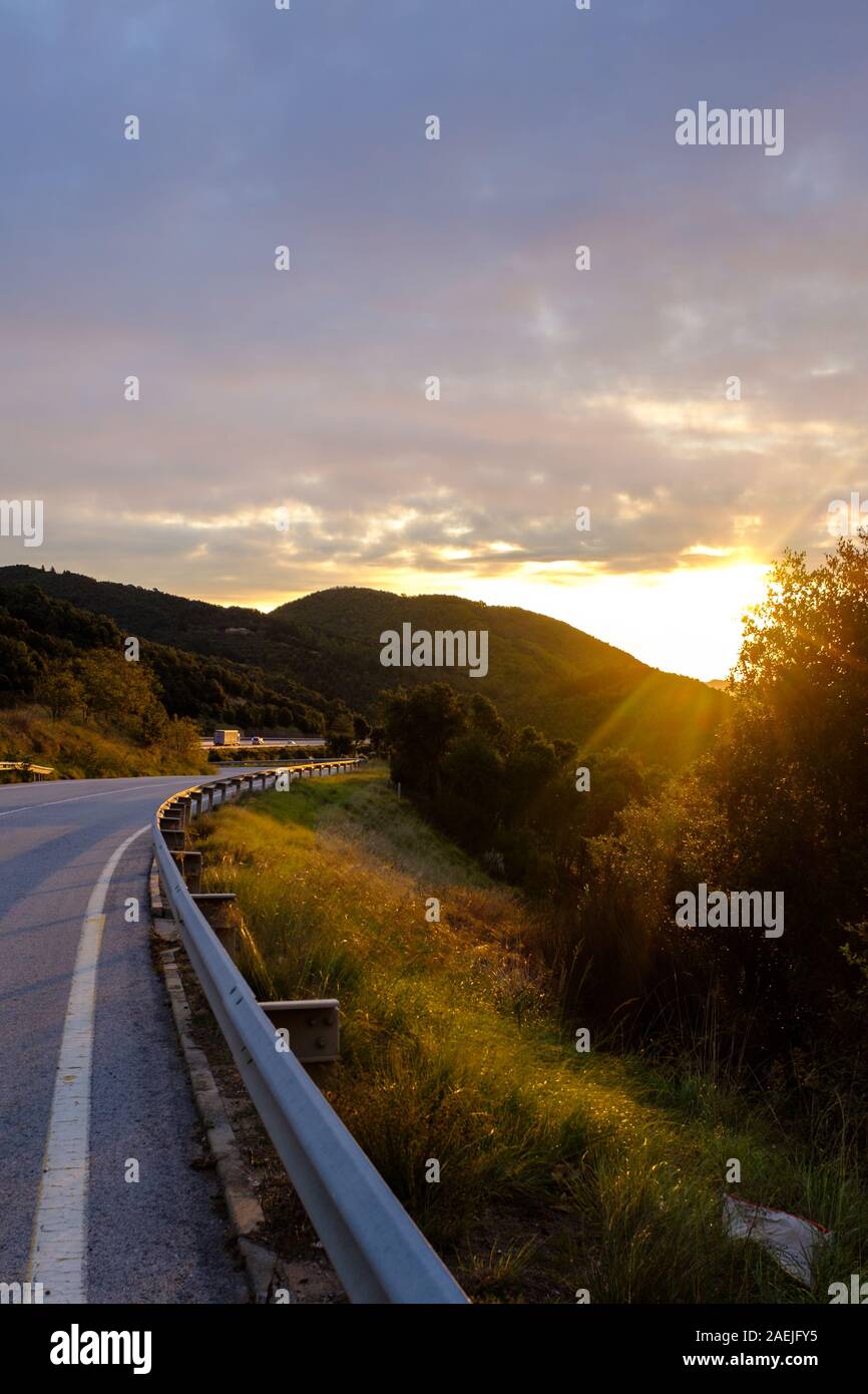Leere Mountain Road Highway mit Metall Barriere Zaun auf einen Sonnenaufgang Landschaft auf eine morgendliche Szene Stockfoto