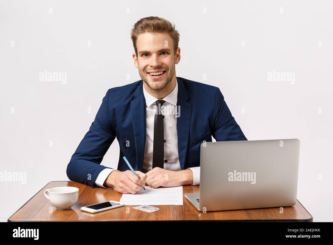 Geschäfts-, Büro- und Unternehmenskonzept. Schöne, freundliche Blonde bärtigen Kerl in klassischen Anzug, Sitzen, Tisch, Schreibtisch mit Laptop, Papiere Stockfoto