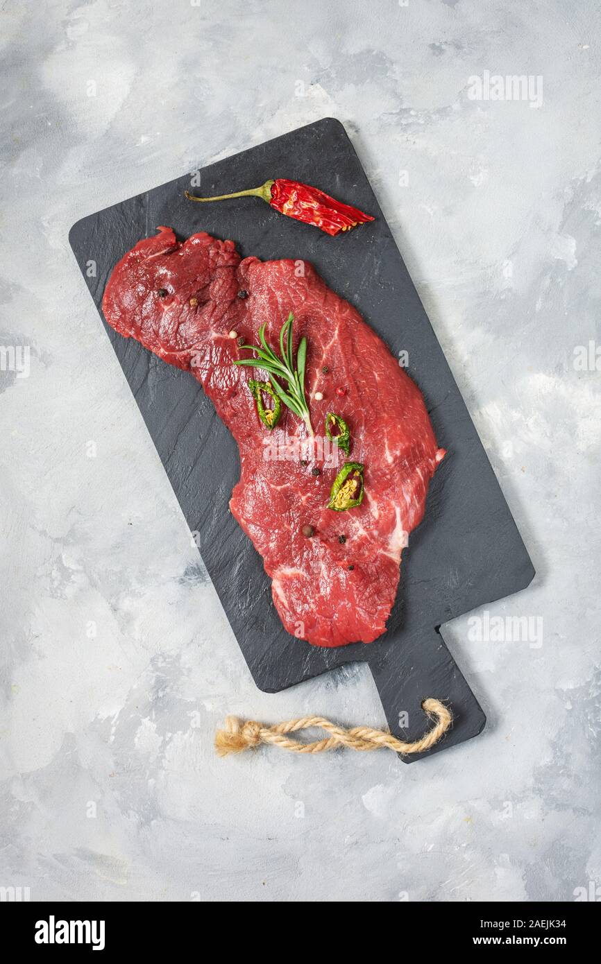 Rohe frische marmoriertes Fleisch Steak und Würzmittel auf konkreten Hintergrund. Ansicht von oben Stockfoto