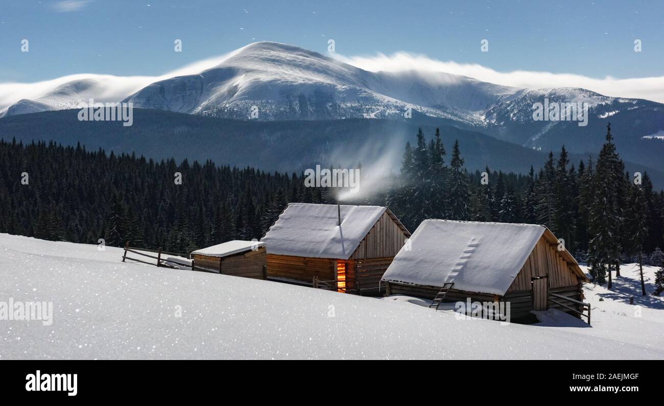 Fantastische Nacht Landschaft durch den Mond Licht leuchten. Dramatische winterliche Szene mit schneebedeckten Haus. Weihnachten Konzept Stockfoto