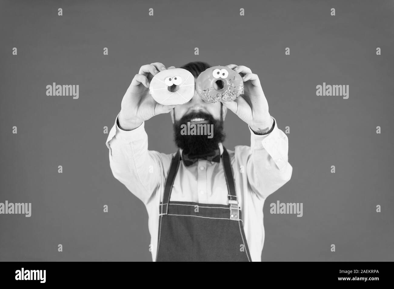Ihr Süßes zum Dessert erfüllen. Der bärtige Mann mit Donut Dessert auf Augen. Professionelle Bäcker Spaß mit Dessert essen. Lustige dessert Gläser. Stockfoto