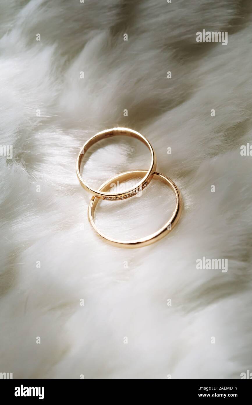 Zwei goldene Hochzeit Ringe liegend auf weißem Fell Hintergrund Stockfoto