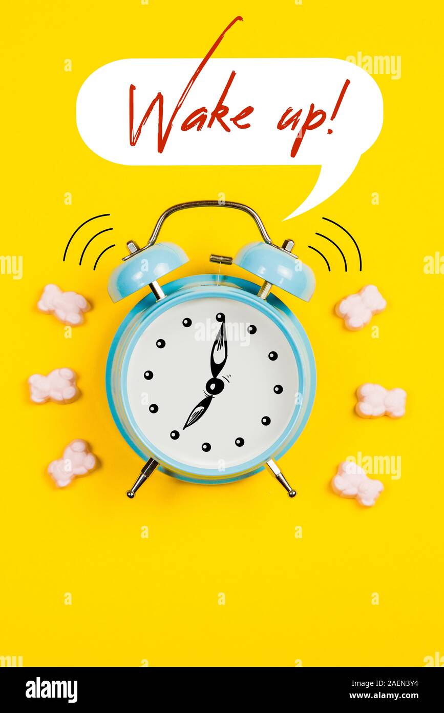 Blau Wecker mit Grafiken und Text Wake up auf gelbem Hintergrund Stockfoto