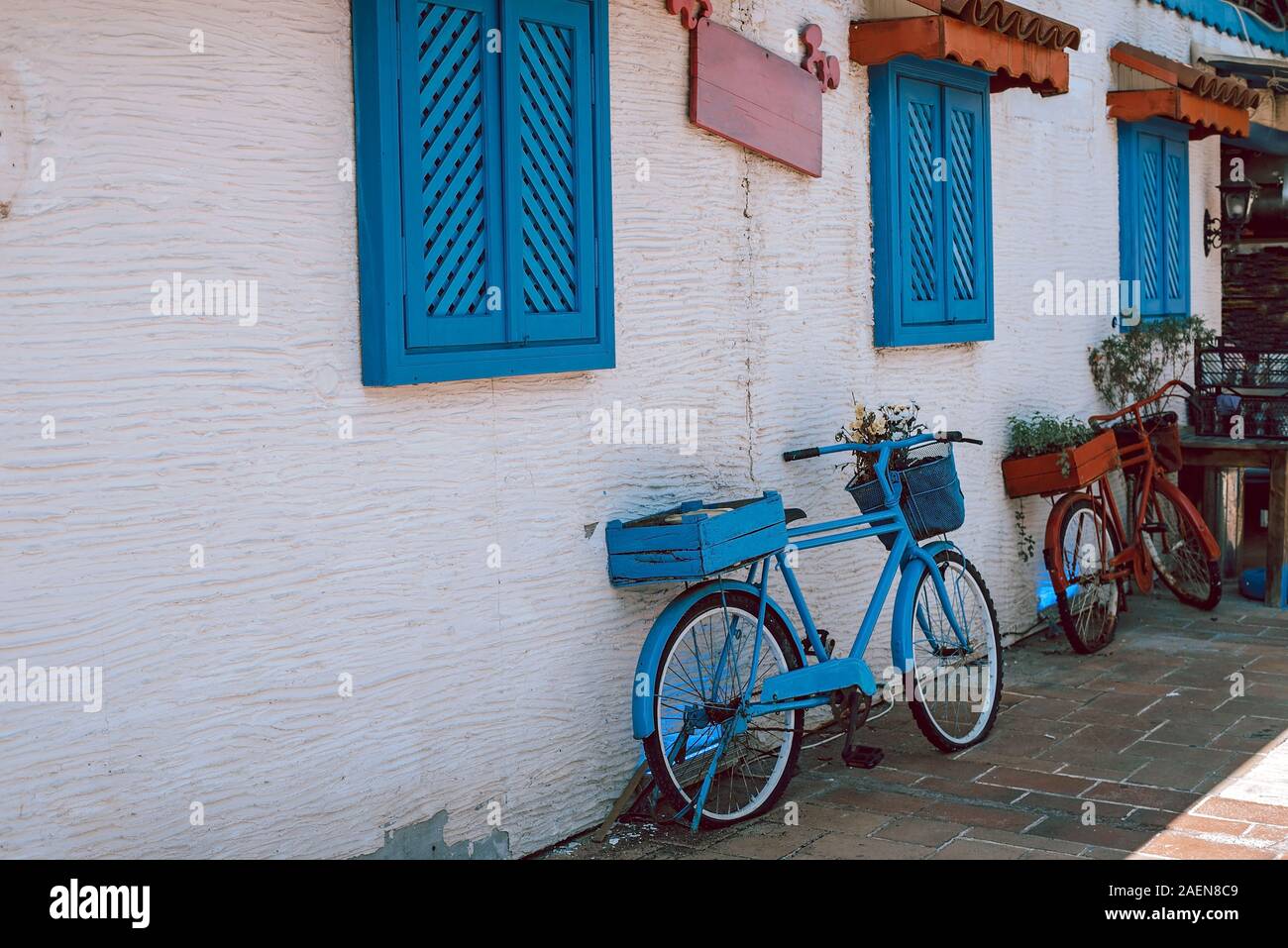 Blaue Fahrräder in der Nähe von weißen Wand mit blauen Fenstern im Freien. Stockfoto