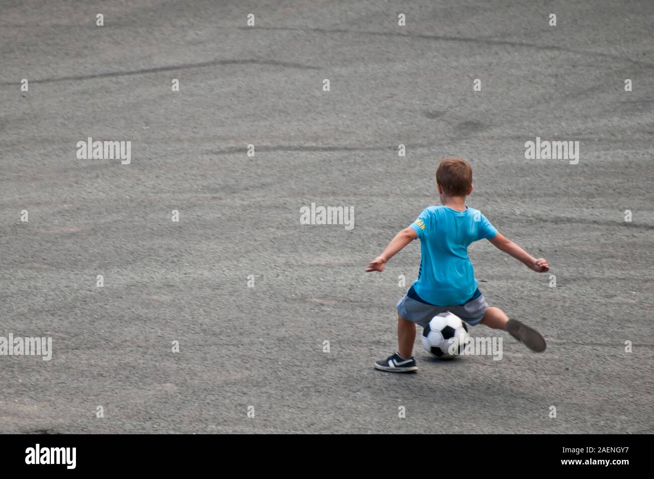 Kind mit einem blauen T-Shirt shooting ein Fußball Stockfoto