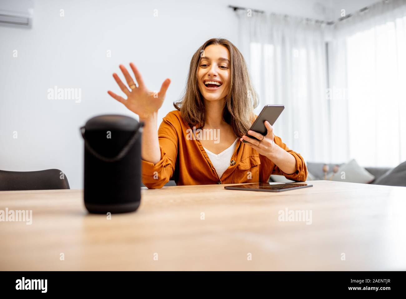 Junge fröhliche Frau controlling home Geräte mit einem Sprachbefehle, um eine Smart Spalte zu Hause sprechen. Konzept der "Smart Home" und Sprachsteuerung Stockfoto