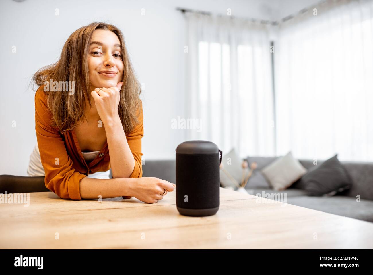 Portrait einer jungen und fröhliche Frau mit einem Smart wireless Spalte zu Hause. Konzept der "Smart Home" und Sprachsteuerung Stockfoto