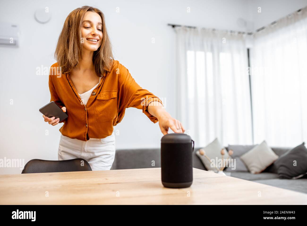 Junge Frau Einschalten wireless smart Spalte zu Hause. Konzept einer Smart Home wireless Geräte. Konzept der "Smart Home" und Sprachsteuerung Stockfoto