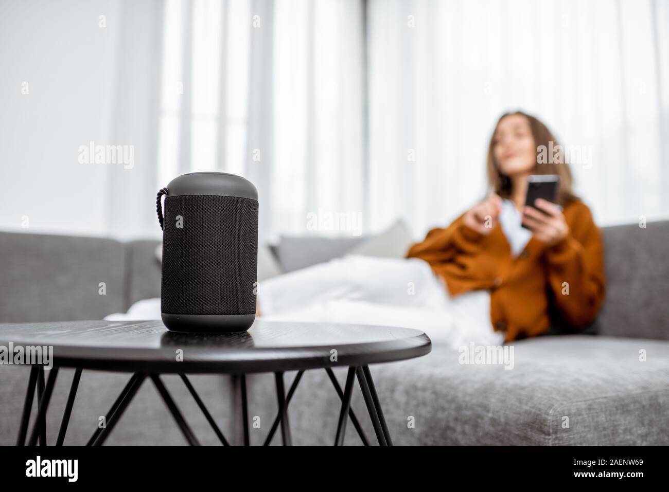 Smart wireless Spalte mit einer jungen Frau controlling home Geräte mit Sprachbefehlen auf dem Hintergrund zu Hause Stockfoto