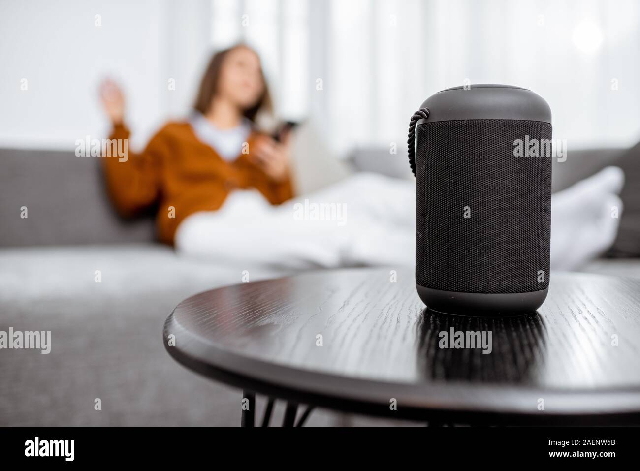 Smart wireless Spalte mit einer jungen Frau controlling home Geräte mit Sprachbefehlen auf dem Hintergrund zu Hause Stockfoto