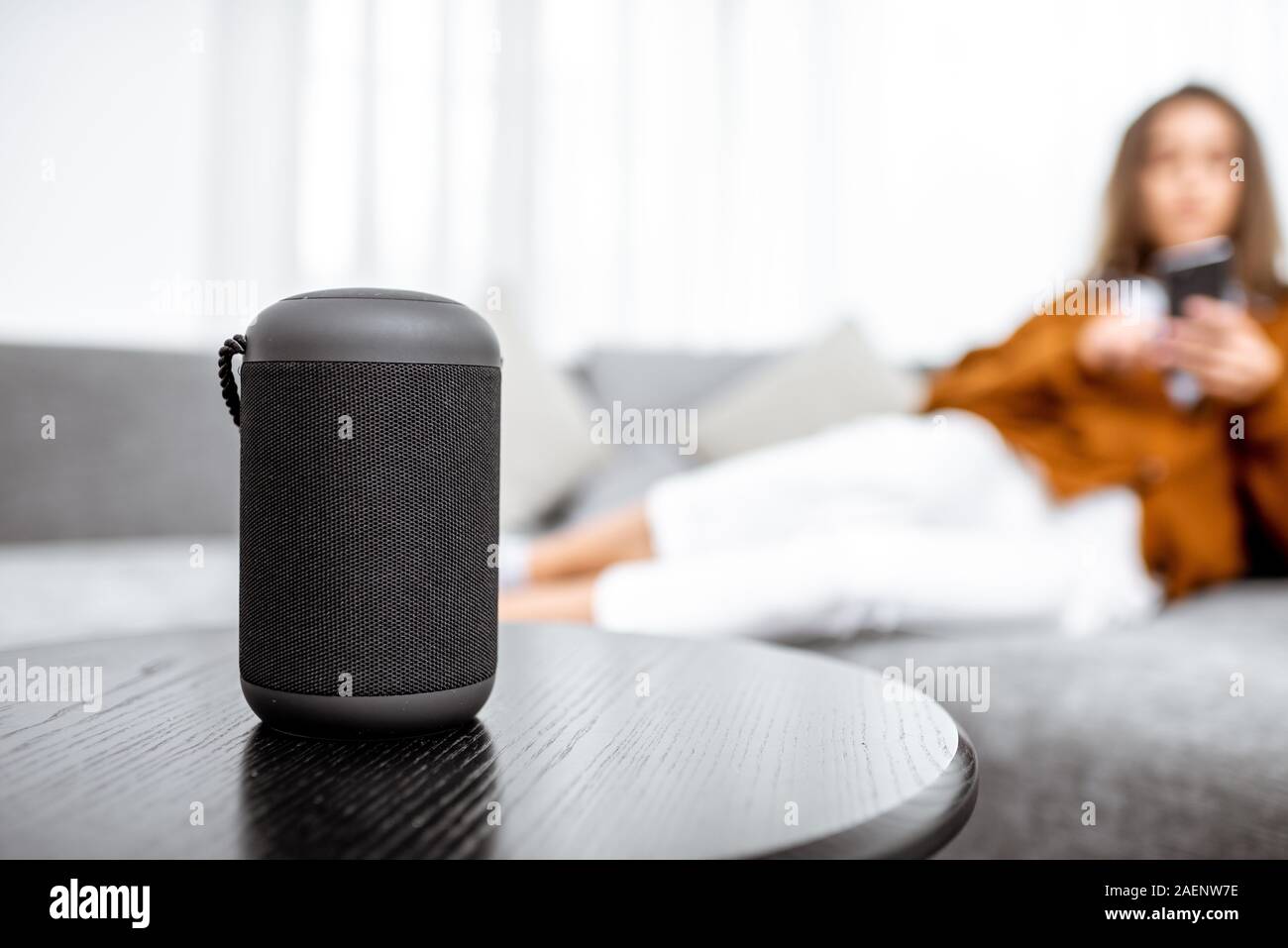 Smart wireless Spalte mit einer jungen Frau controlling home Geräte mit Sprachbefehlen auf dem Hintergrund zu Hause Stockfoto