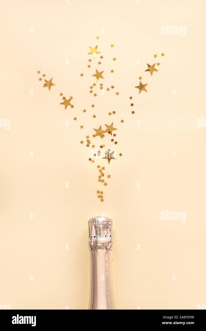 Champagner Flasche mit Konfetti Sterne auf goldenen festlichen Hintergrund. Weihnachten, Geburtstag oder Hochzeit Feier Konzept. Flach, kopieren. Stockfoto