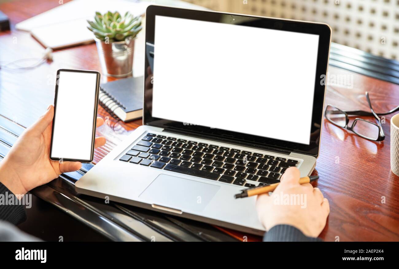 Handy und Laptop mit weißen leeren Bildschirme, Mann bei der Arbeit in seinem Büro Schreibtisch, geschäftlichen Hintergrund, kopieren. Stockfoto