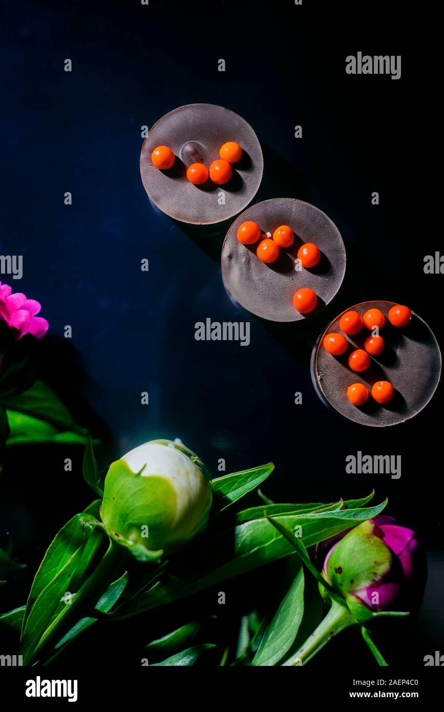 Bouquet von wunderschönen Blumen und Schokolade auf Holz- Oberfläche Stockfoto