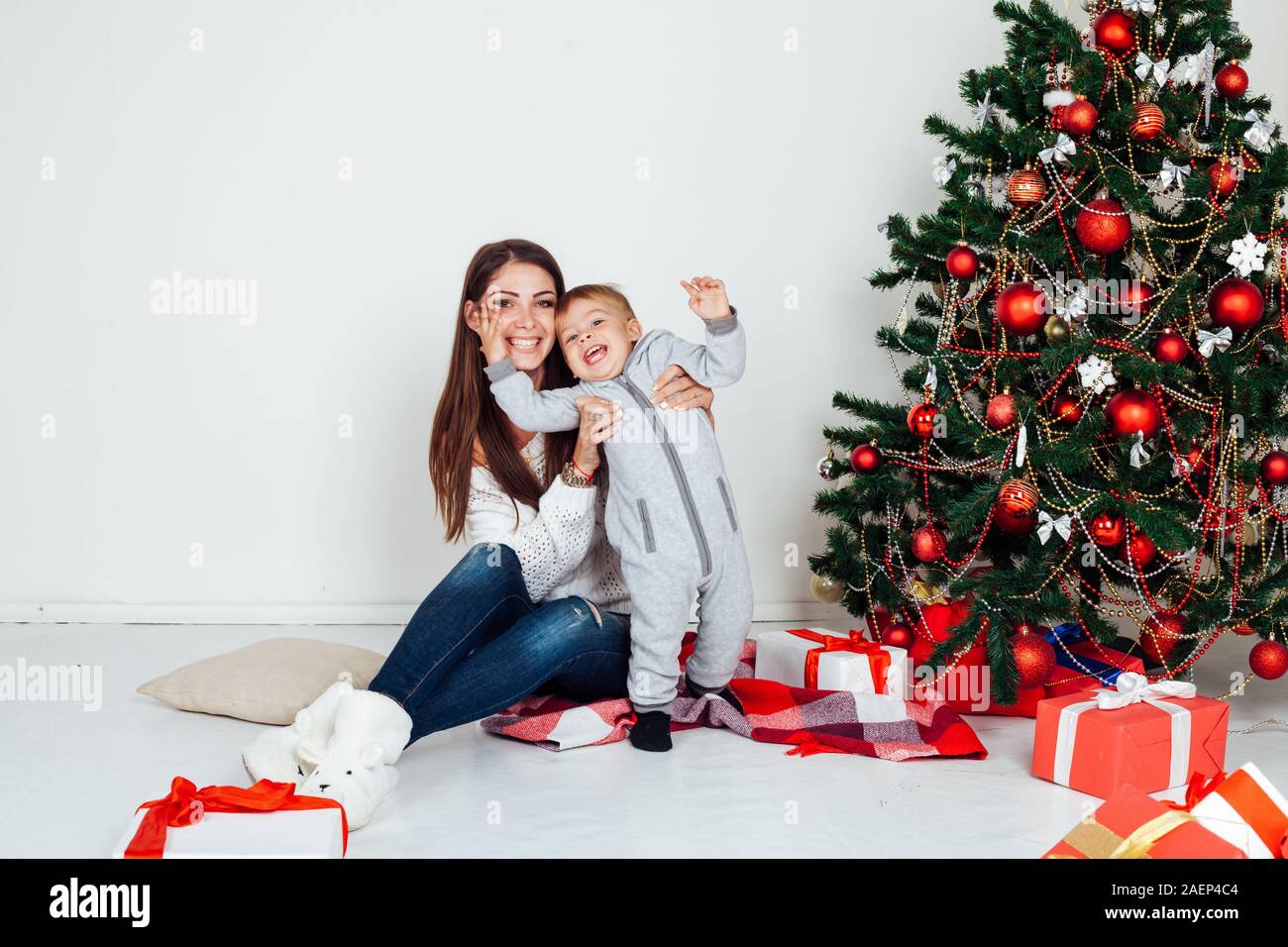 Mutter und kleinen Jungen am Weihnachtsbaum mit Geschenken 1. Stockfoto