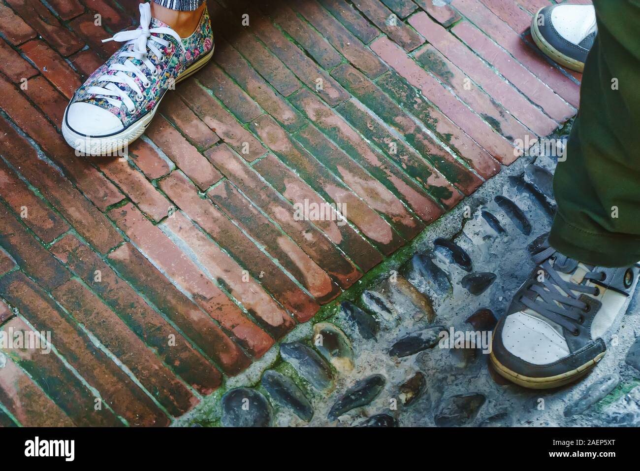 Beine von Mann und Frau im Sport Schuhe und stehend auf Bürgersteig Hintergrund in Italien Stockfoto