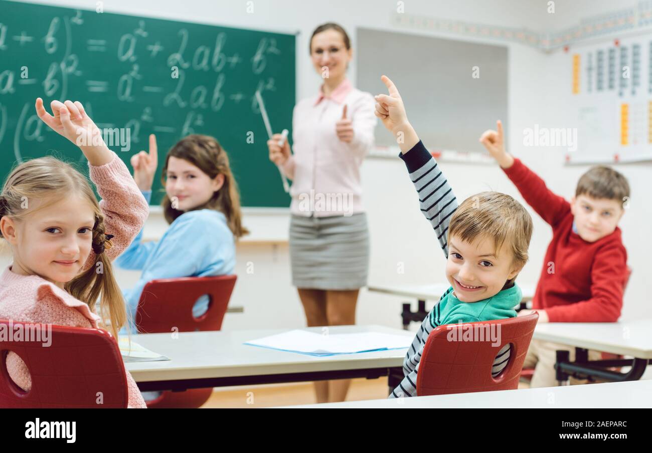 Studenten in der Klasse heben die Hände, um eine Frage zu beantworten Stockfoto