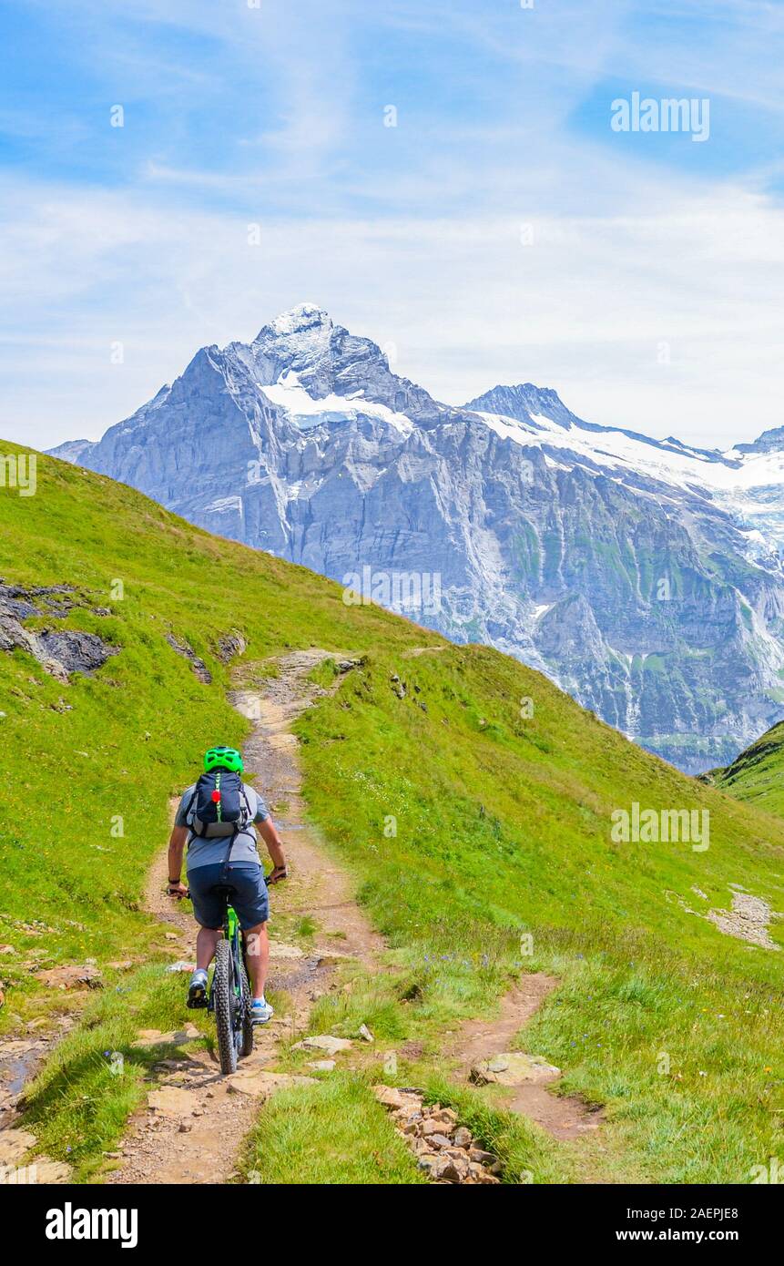 Biker Reiten in atemberaubenden alpinen Landschaft. Schneebedeckte Berge im Hintergrund. Auf den Spuren von Grindelwald zu bachalpsee fotografiert. Aktiven Urlaub, Menschen, Sport. Stockfoto