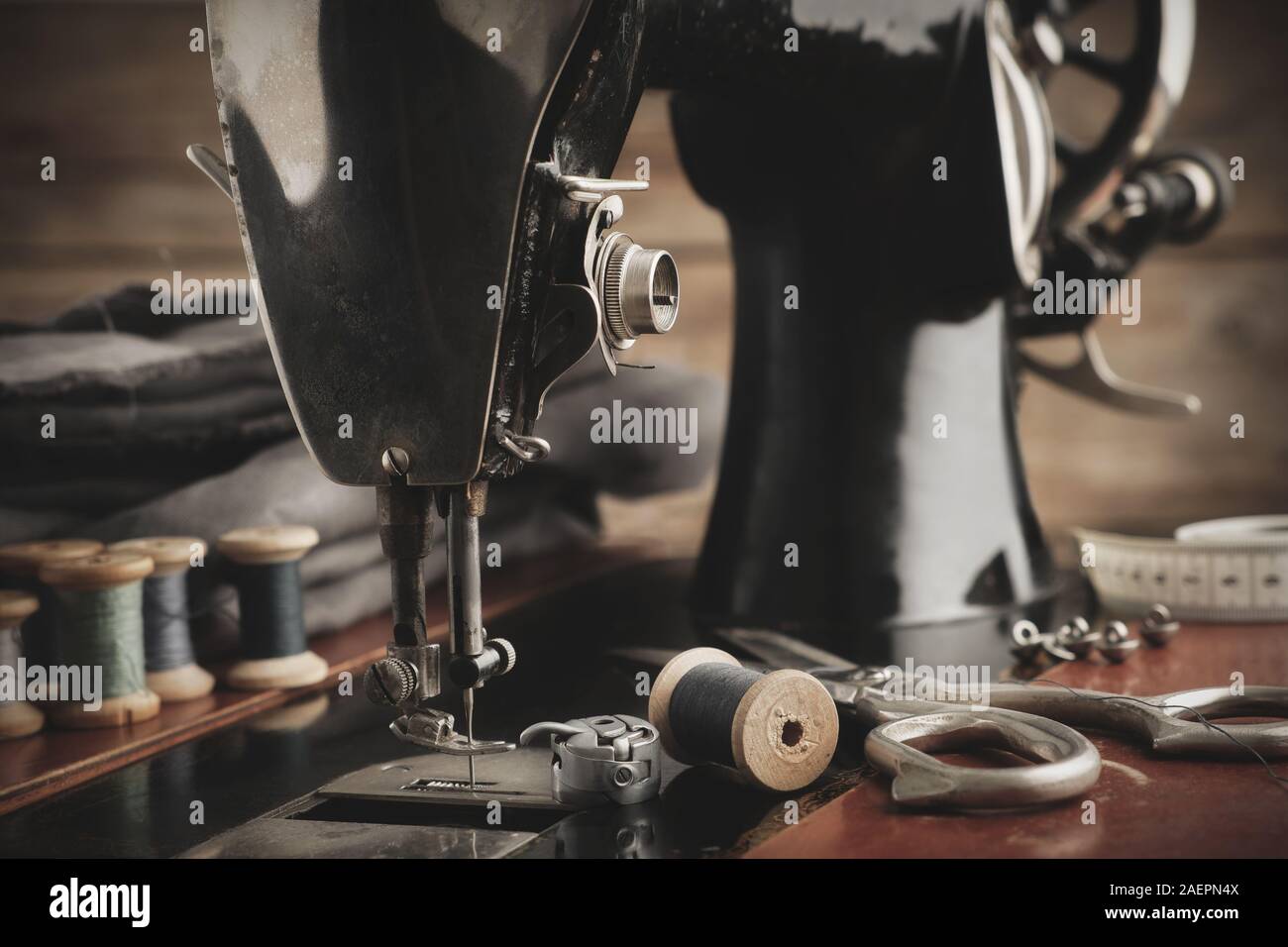 Alte antike Nähmaschine hautnah. Tailoring Schere, Tücher und Holz- Spulen des Threads. Retro Workshop anpassen. Stockfoto
