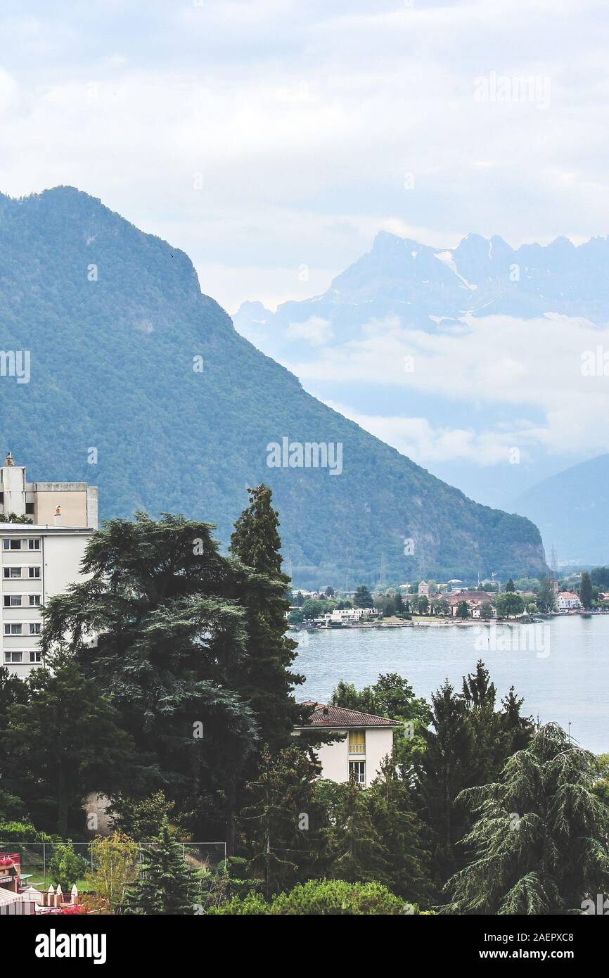 Berühmte Stadt Montreux in der Schweiz an einem nebligen Tag. Gebäude, die von schönen See Genf, der Schweizer Alpen im Hintergrund. Beliebtes Ausflugsziel, Schweizer Riviera. Vertikale Bild. Stockfoto