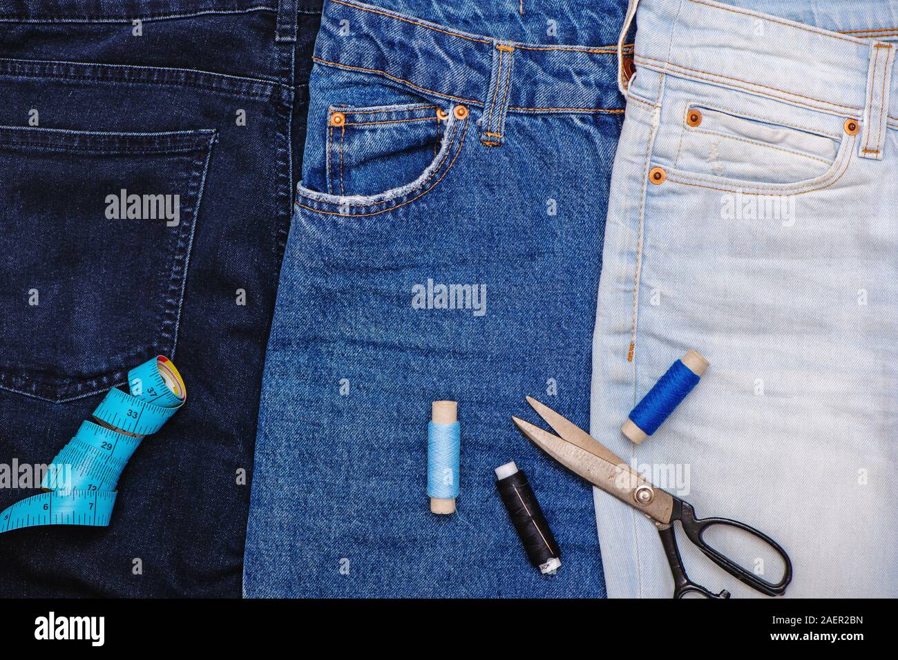 Drei Paar Jeans mit Schere, Gewinde und passen. Upcycle Konzept. Stockfoto