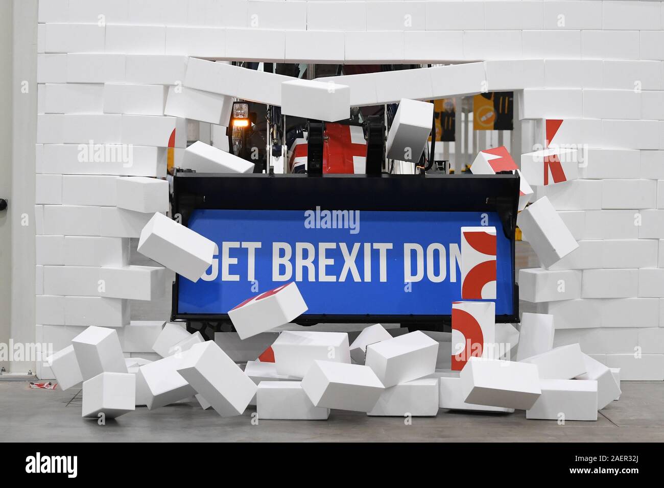 Premierminister Boris Johnson Antriebe eine Union Flag-themed JCB, mit den Worten 'Brexit getan" innerhalb der Bagger Schaufel, durch eine gefälschte Wand prangt das Wort "verkehrsinfarkt", bei einem Besuch in JCB Cab Manufacturing Center in Uttoxeter, während auf der allgemeinen Wahlkampagne Trail. Stockfoto