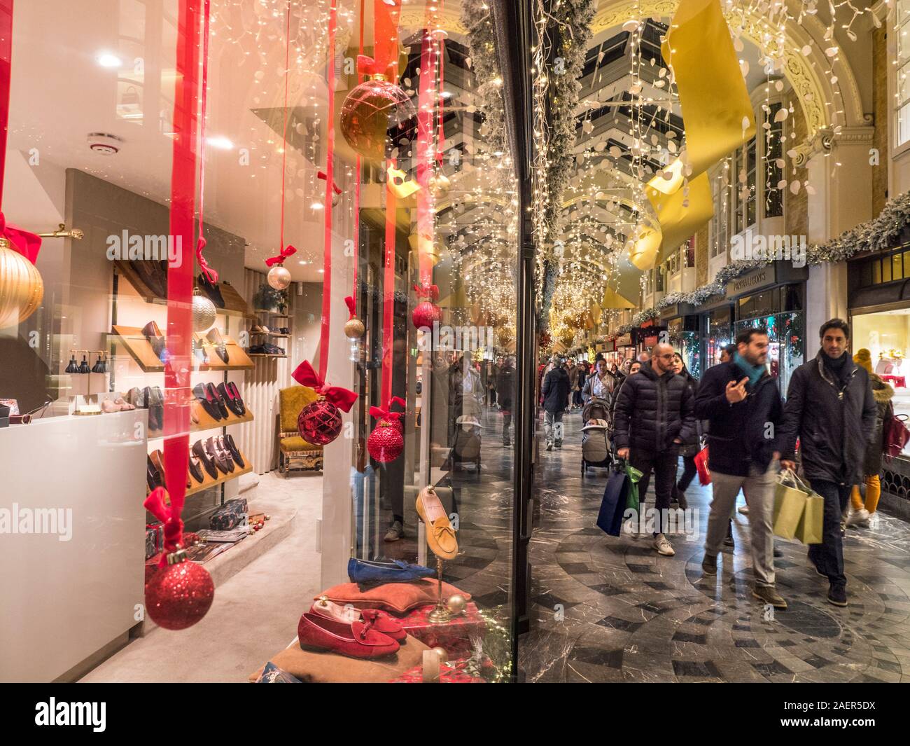 BURLINGTON ARCADE WEIHNACHTEN FESTLICHE SCHAUFENSTER WEIHNACHTEN SHOPPING EINKAUFSTASCHEN INNEN charmante alte Welt Burlington Arcade in seinem 200. Jahr in Piccadilly mit traditionellen Weihnachtsdekorationen und Shopper London UK Stockfoto