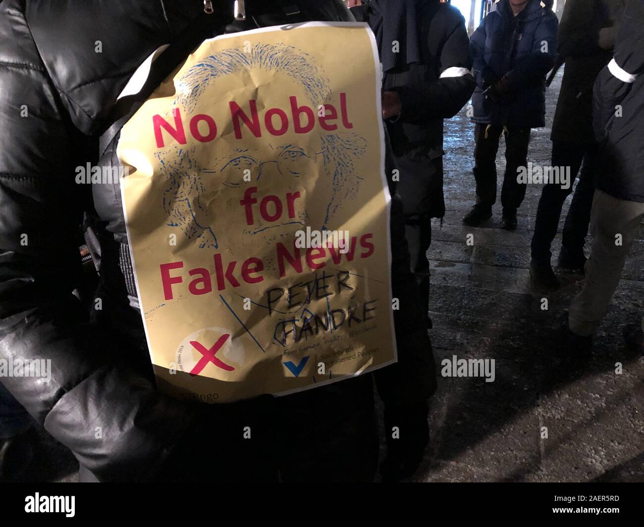 10 Dezember 2019, Schweden, Stockholm: Eine Frau zeigt auf der Norrmalmstorg mit einem Papier mit der Aufschrift "Kein Nobelpreis für gefälschte Nachrichten" gegen die Verleihung des Nobelpreises für Literatur 2019 an den österreichischen Schriftsteller Peter Handke wegen seiner umstrittenen Position in der jugoslawischen Konflikt. Foto: Steffen Trumpf/dpa Stockfoto