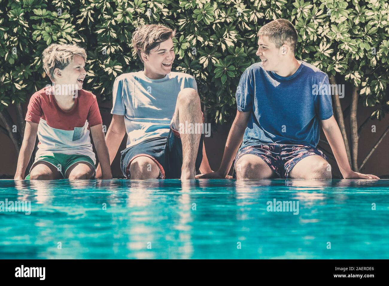 Junge männliche genießen Sie Tage der Schule entspannen im Pool. Lächelnd Teenager sitzen am Rand des Pools. Glückliche Menschen genießen Sie den Sommer Stockfoto